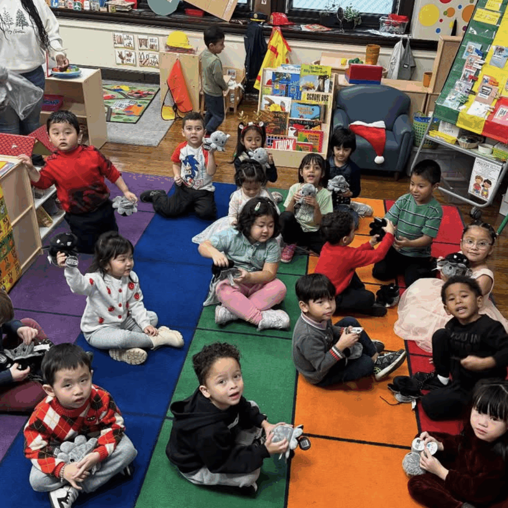 Young students at Southwark School sit together on a classroom rug during a play-based learning activity, engaging with toys and classmates in an early childhood classroom.