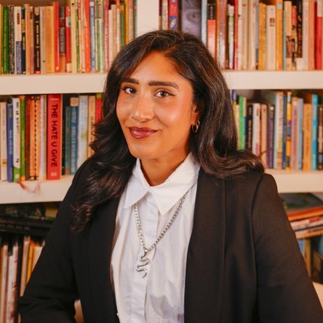 Dr. Cybil Yakira, Assistant Principal of Southwark School, smiles in front of bookshelves, wearing a black blazer and white shirt.